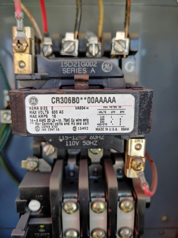 Close-up of a GE motor starter with electrical wires attached. The label shows the model CR306B0.