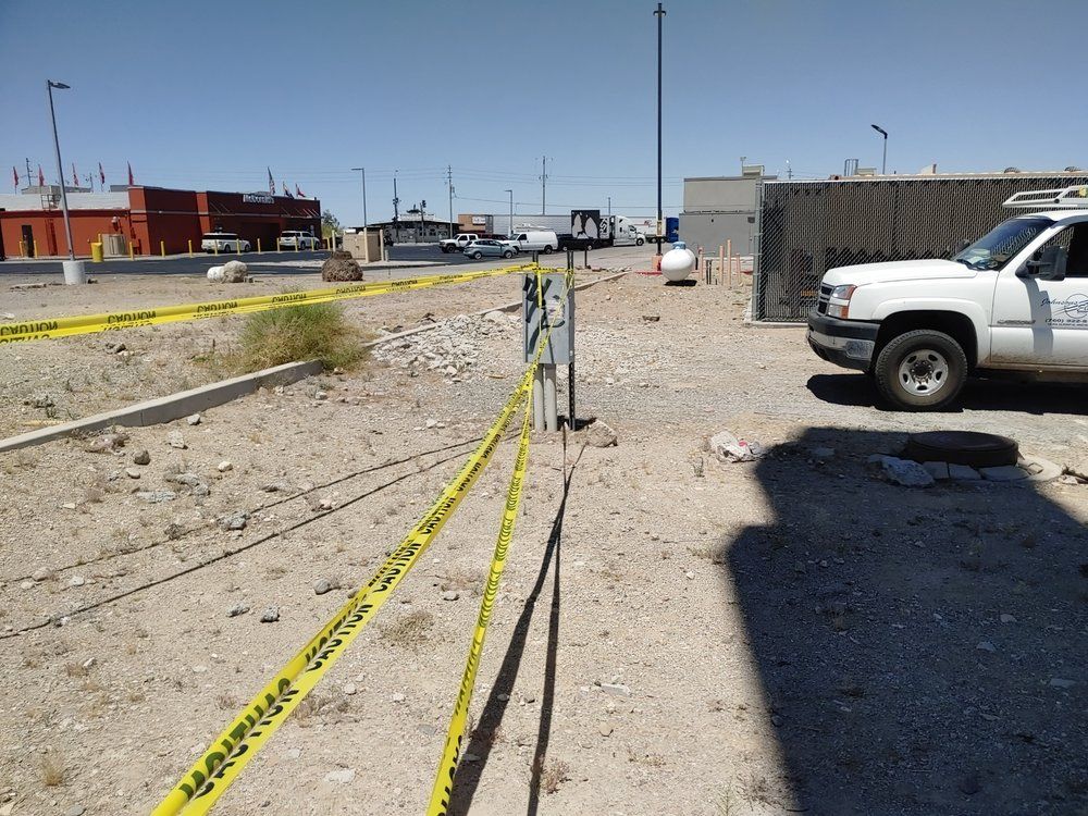Yellow caution tape borders a gravel lot with a parked white truck on a sunny day.