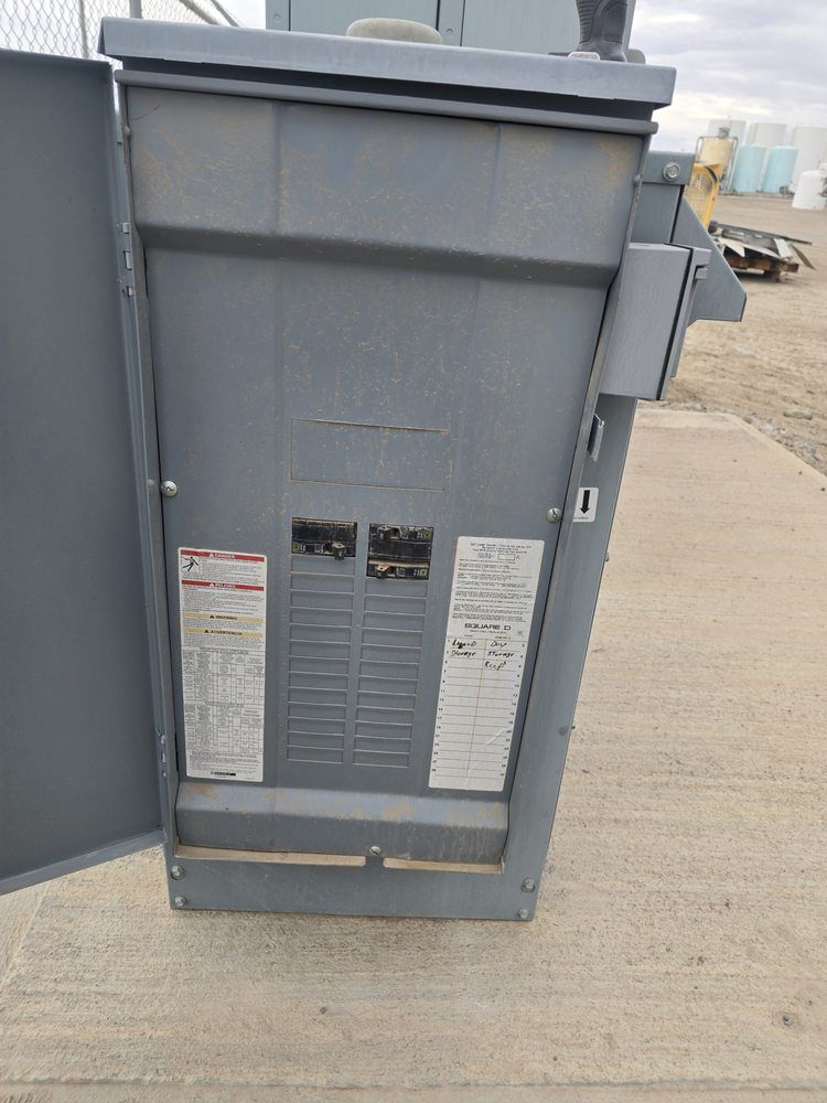 Gray electrical panel with open door on concrete.