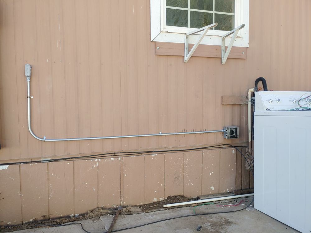Electrical conduit running along a beige house exterior wall, next to a window and washing machine.