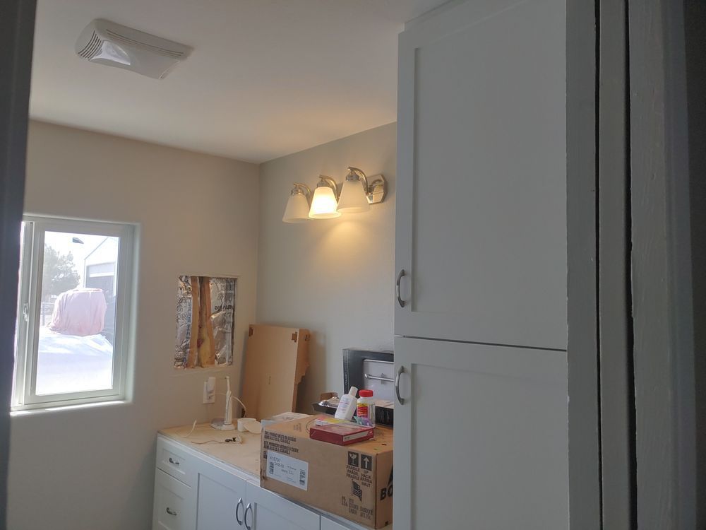 Bathroom with unfinished counter, cabinet, and window; light fixtures on wall.