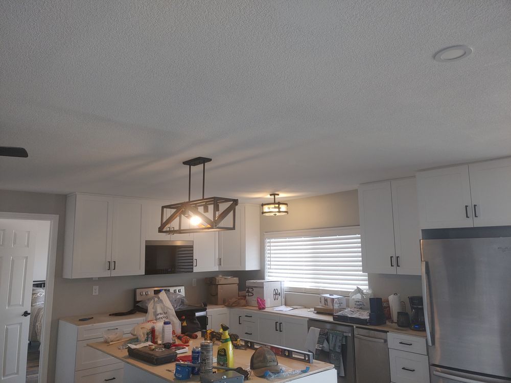 Kitchen interior with white cabinets, stainless steel appliances, and a wooden chandelier.