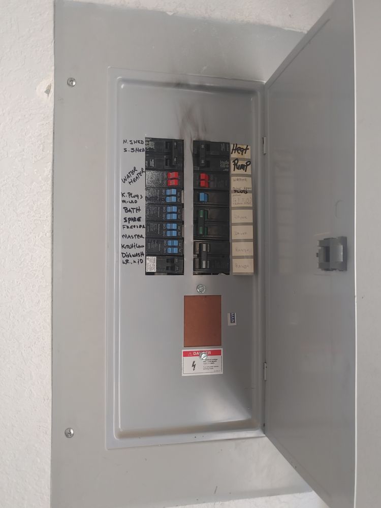 Open gray electrical panel with circuit breakers. Breakers are labeled and cover is ajar.