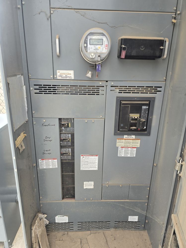 Gray electrical panel with digital meter, circuit breakers, and vents.