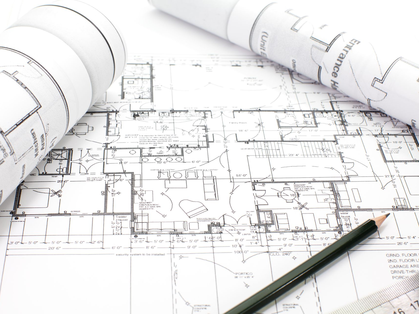 Architectural blueprints with rolled-up plans, pencil, and ruler.