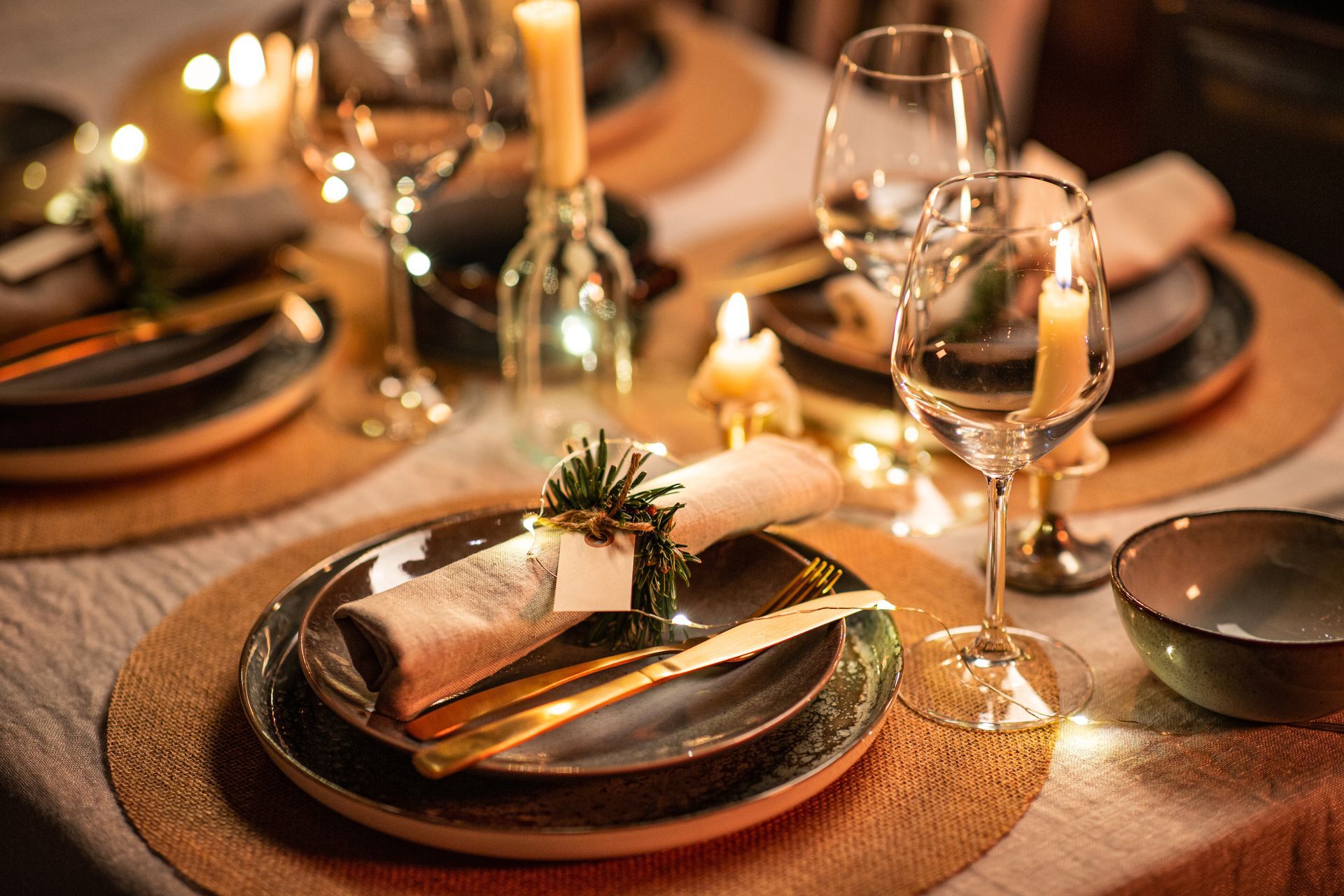 Formal table setting with candles, plates, wine glasses, and gold cutlery for Christmas.