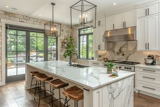 A kitchen with black and white cabinets, stainless steel appliances, and a large island.