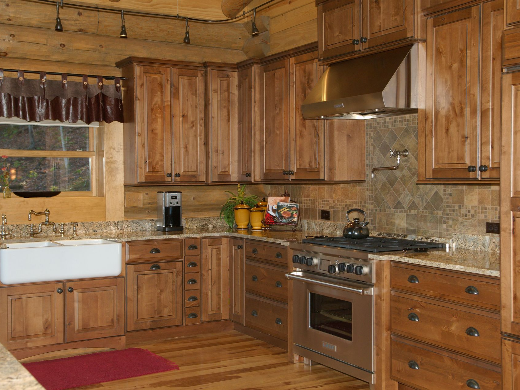 Kitchen with wood cabinets, stone backsplash, stainless steel appliances, and farmhouse sink.