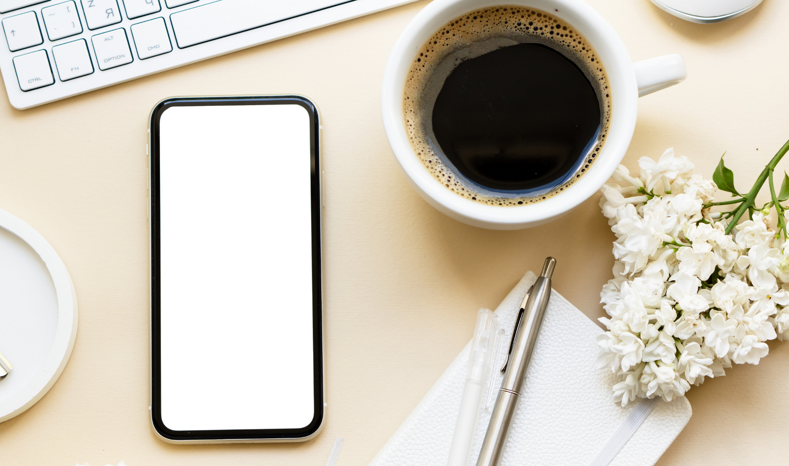 A laptop computer with a cup of coffee and a bud vase with a rose