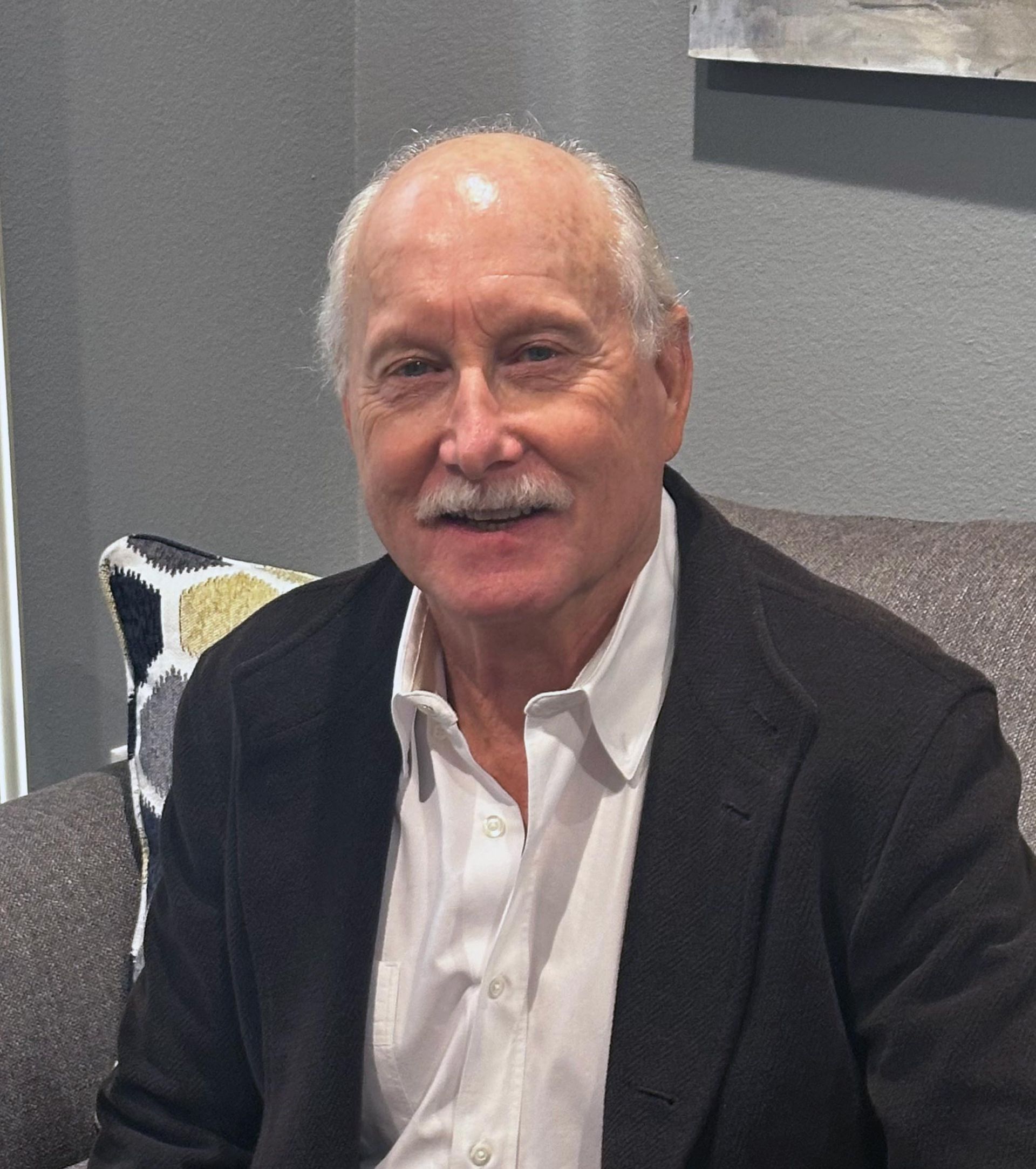 A man in a suit and white shirt is sitting on a couch.