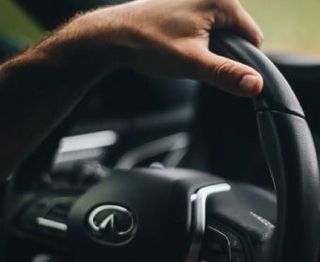 A hand gripping the top of a steering wheel in a lease car