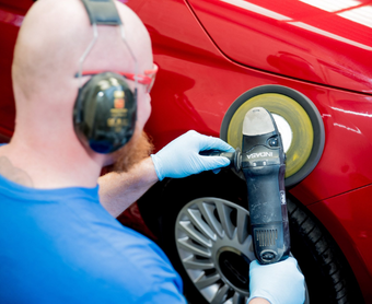 Red car being machine-polished after an accident.