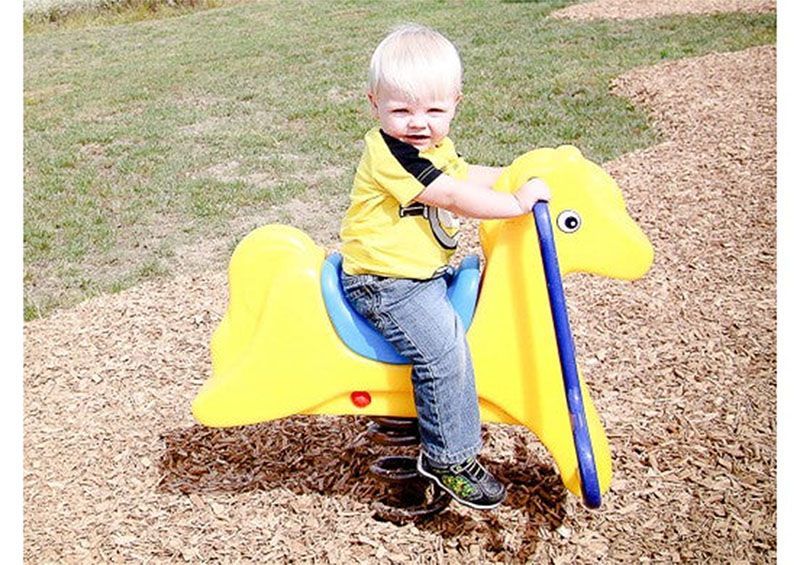 A little boy is sitting on a yellow rocking horse