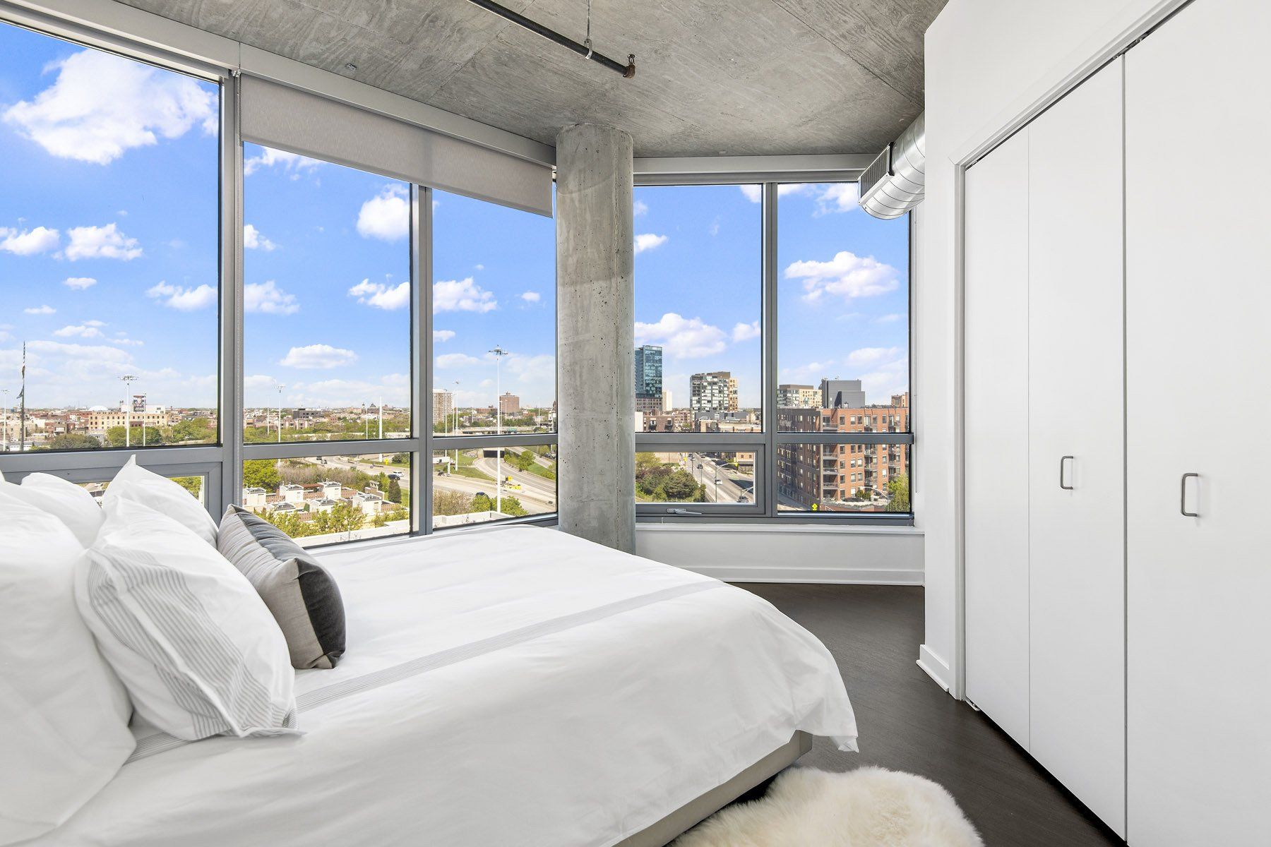 A bedroom with a large bed and lots of windows at Reside on Green Street.