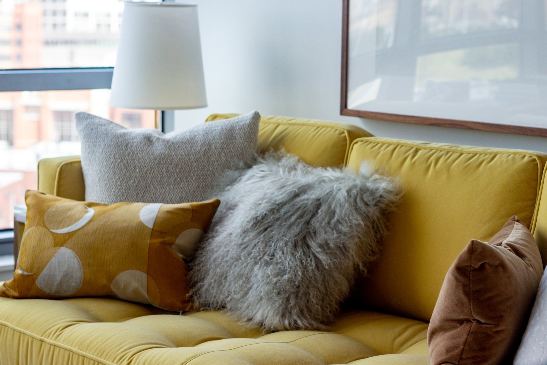 A yellow couch with a lot of pillows on it in a living room at Reside on Green Street.