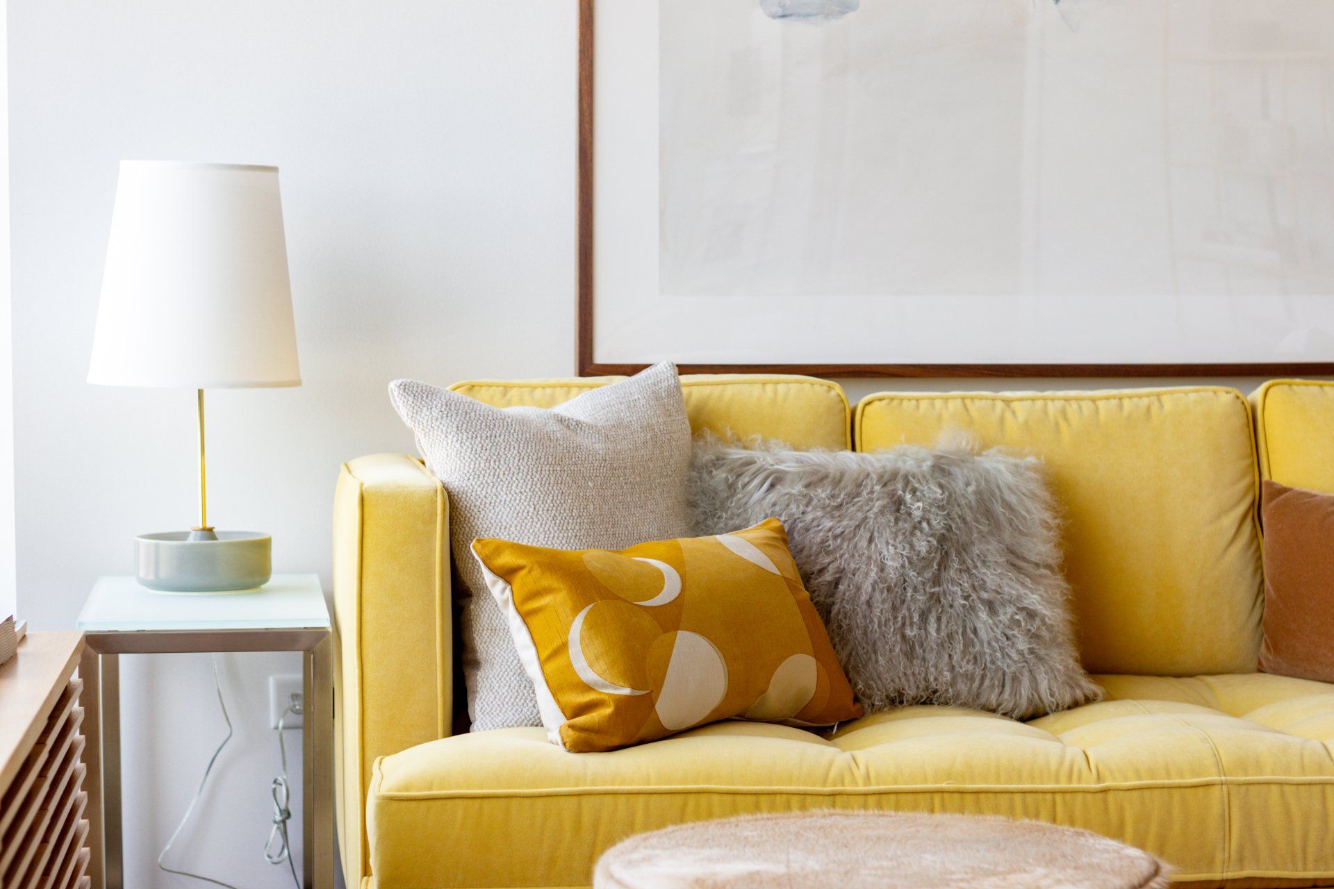A living room with a yellow couch and pillows at Reside on Green Street.