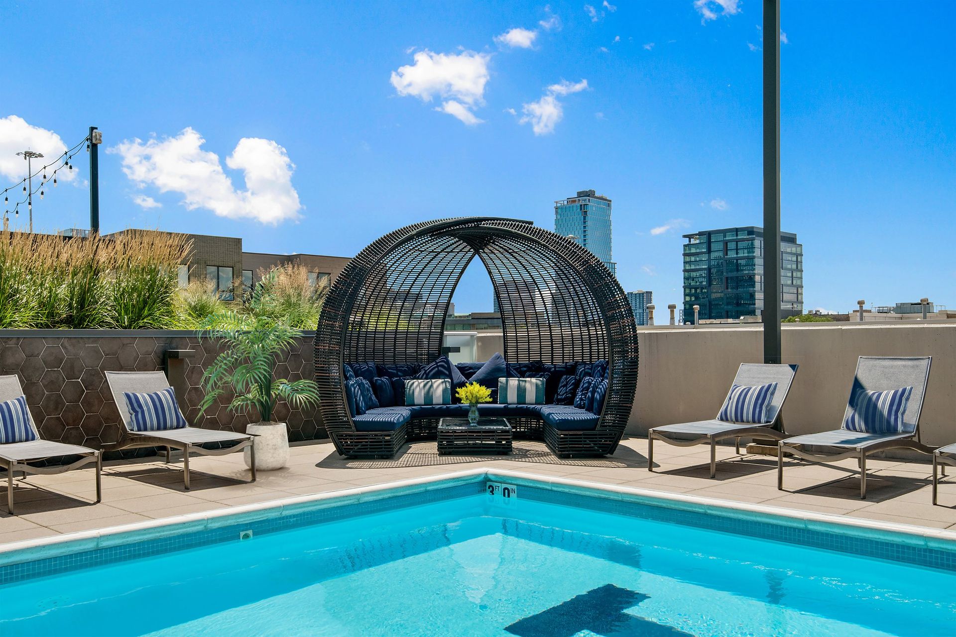 a pool and lounge area with a city skyline in the background