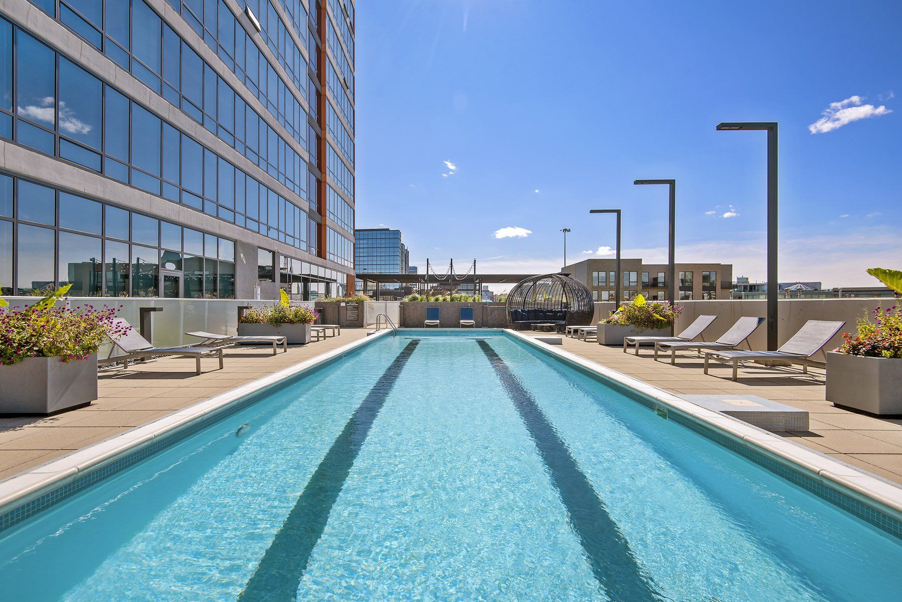 A large swimming pool is surrounded by chairs and a building at Reside on Green Street.
