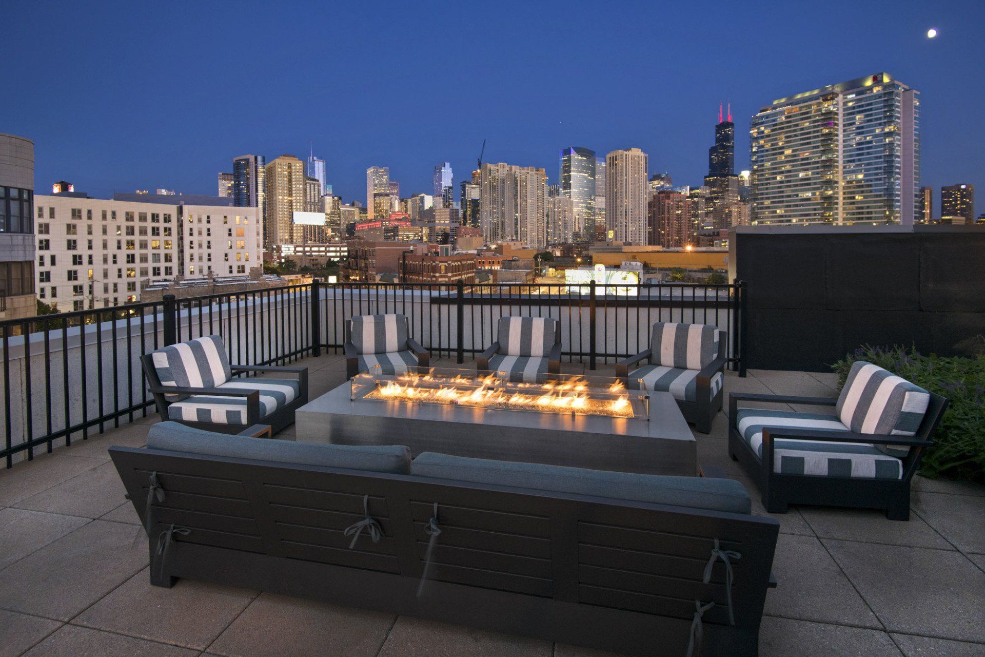A fire pit on a patio with a city skyline in the background at Reside on Green Street.