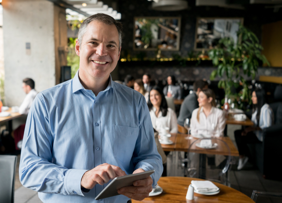 A man is holding a tablet in a restaurant.