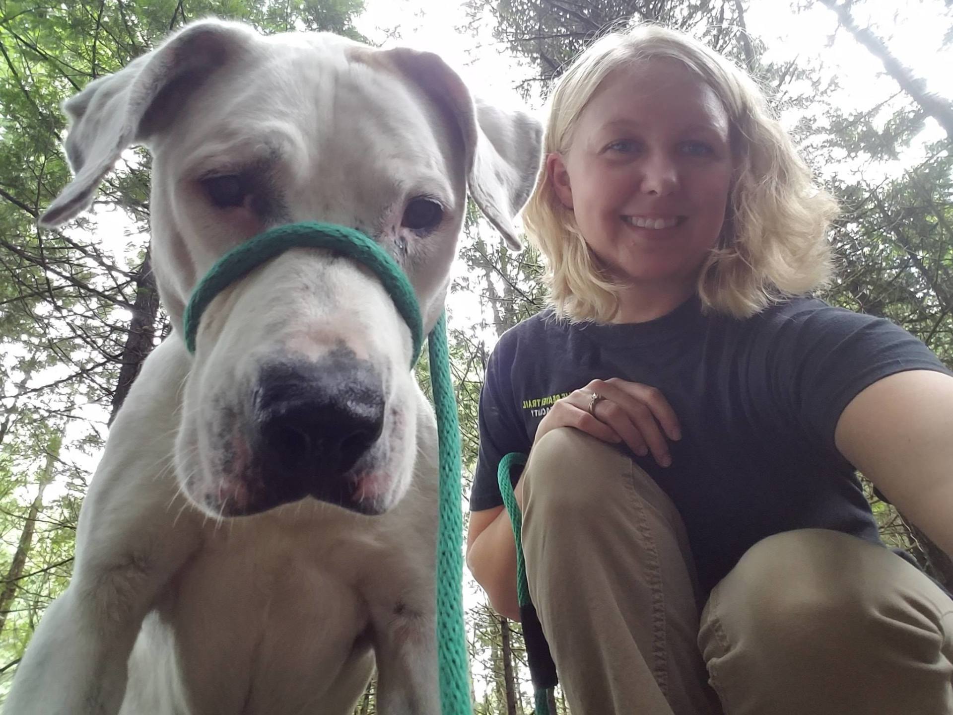 A white dog Standing with a blonde women in a blue shirt
