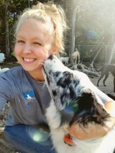 Off the Beaten Trail canine daycare, a women is being licked by a black and white dog