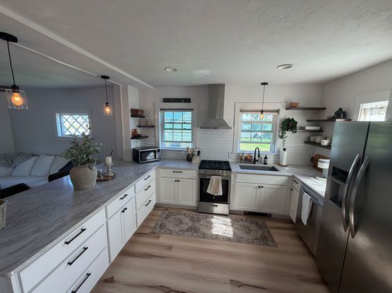 Modern kitchen with white cabinets, stainless steel appliances, and gray countertops.