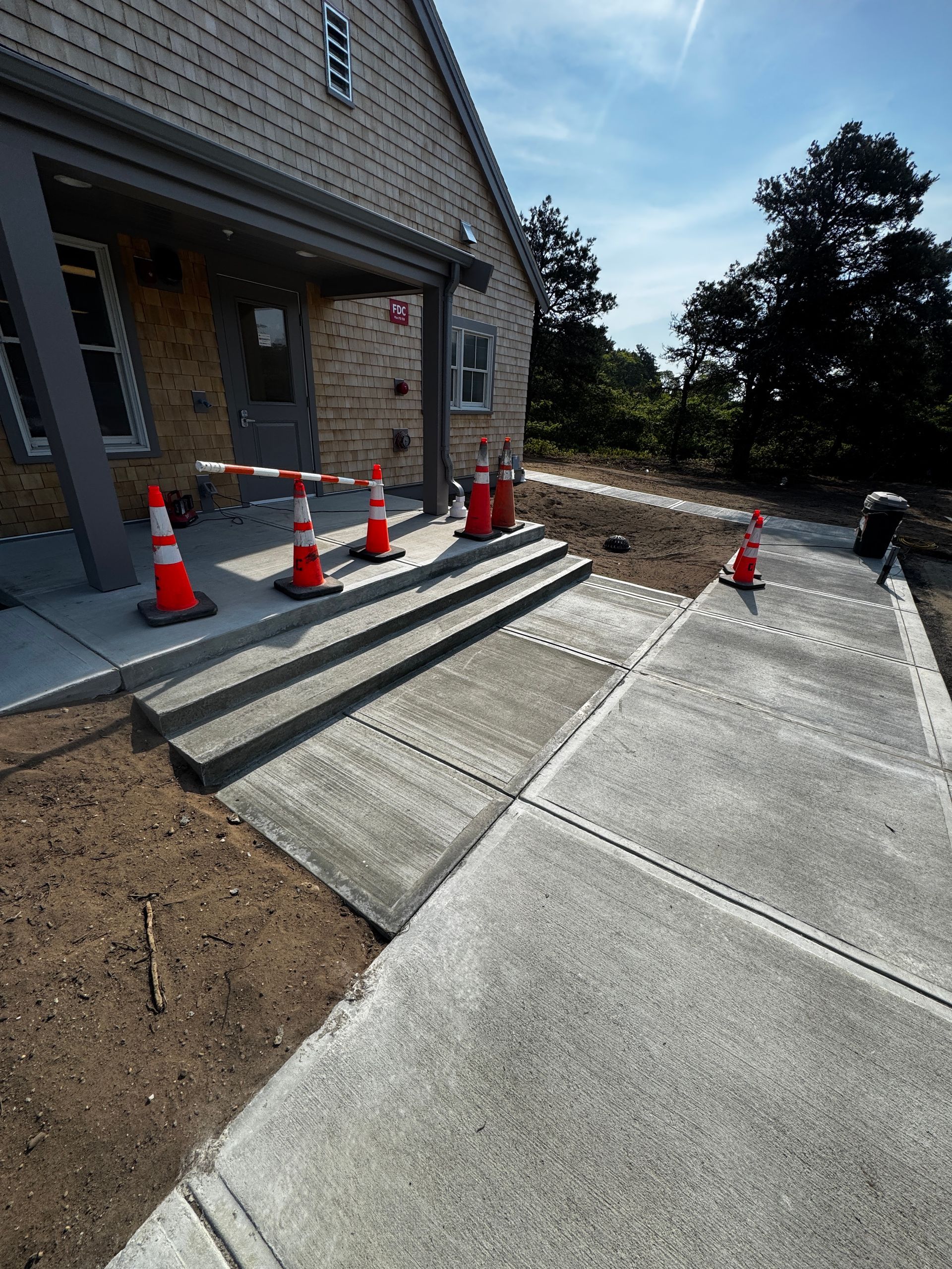 Building with steps and ramp, orange cones, construction area, sunny day.