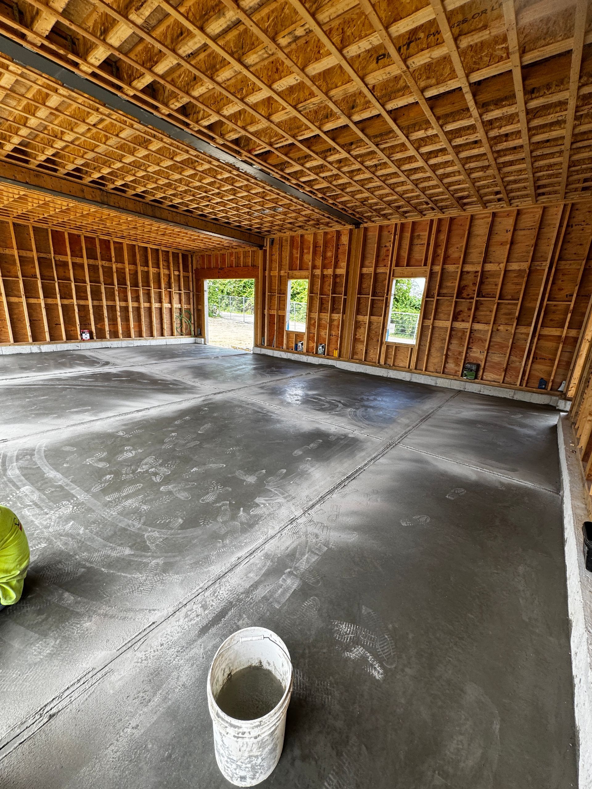 Interior of a building under construction. Unfinished wooden walls and ceiling. Newly poured gray concrete floor.