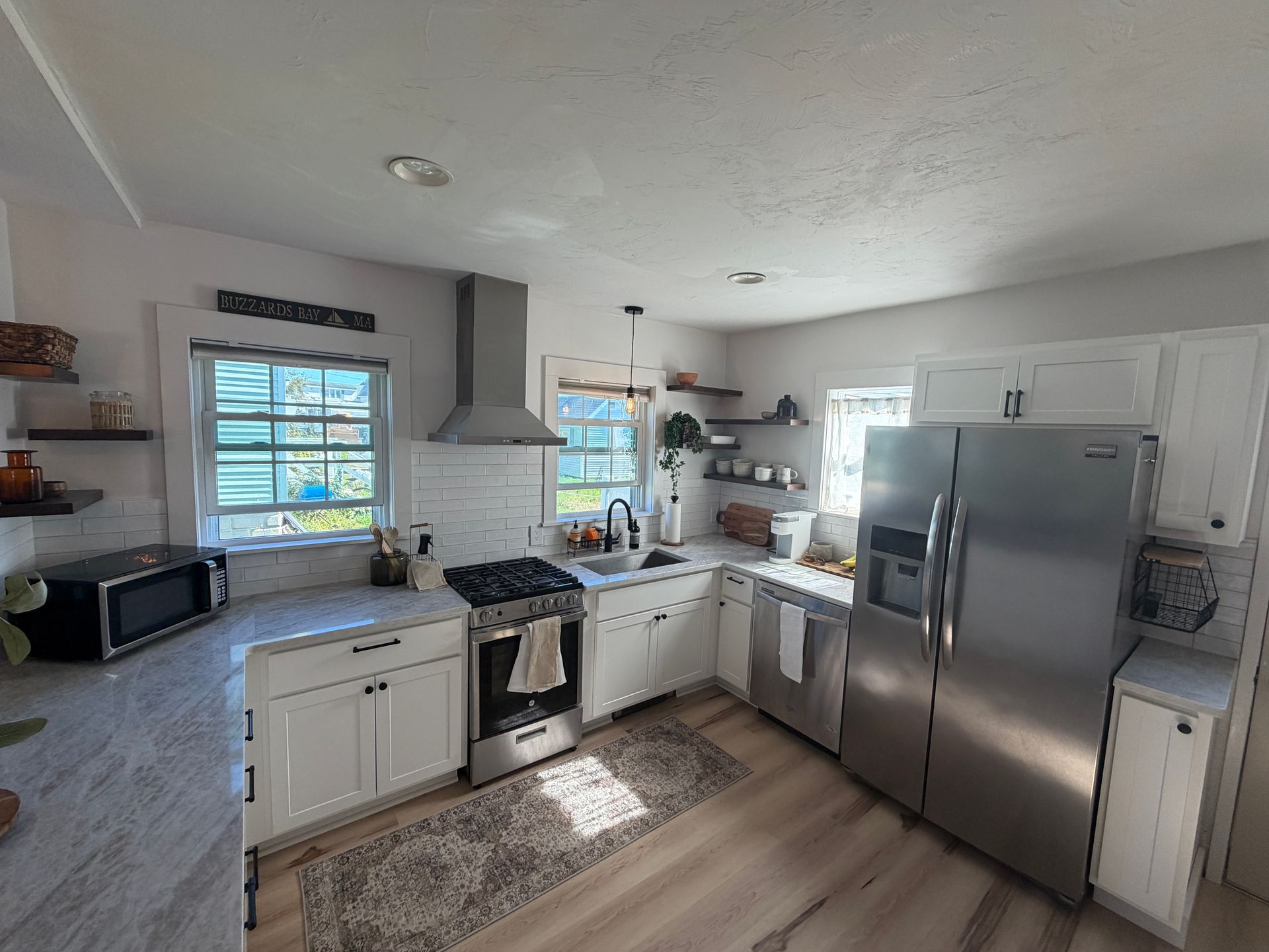 Bright, modern kitchen with white cabinets, stainless steel appliances, and a gray backsplash.