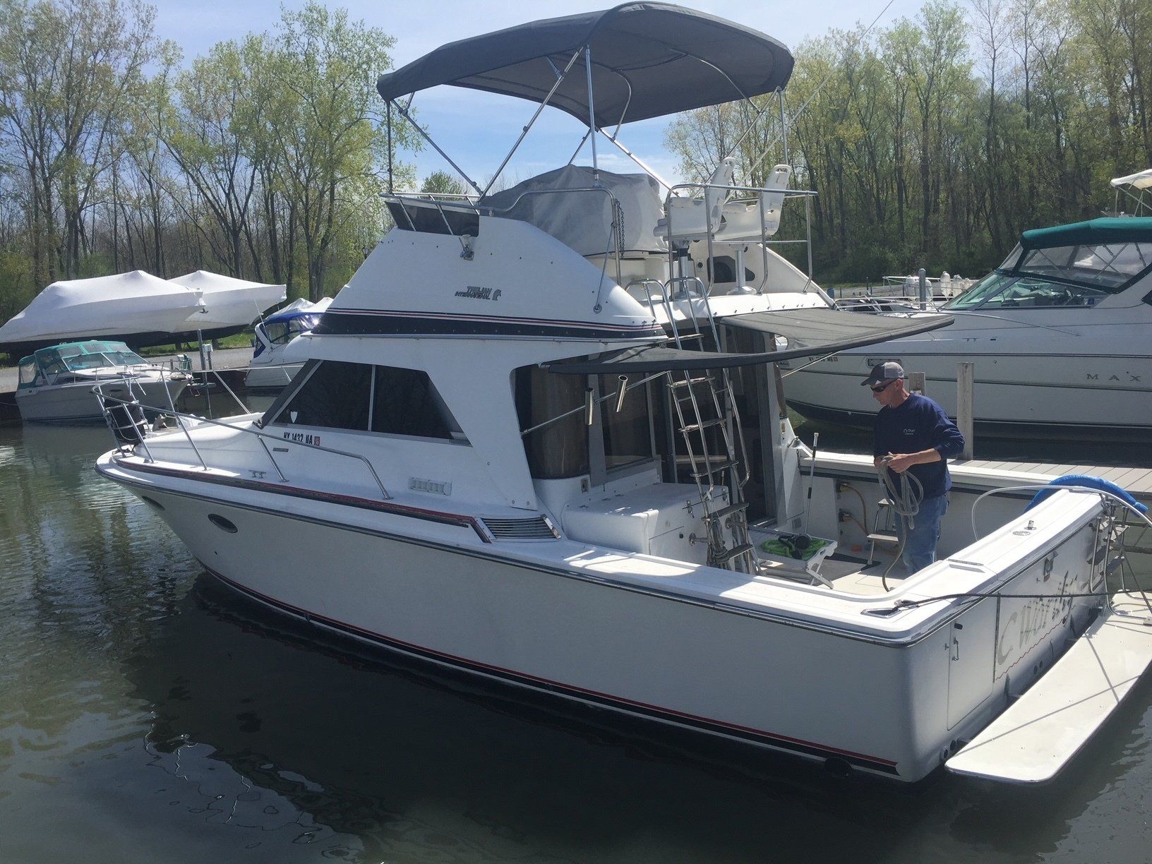 A man is standing on the back of a boat in a marina.
