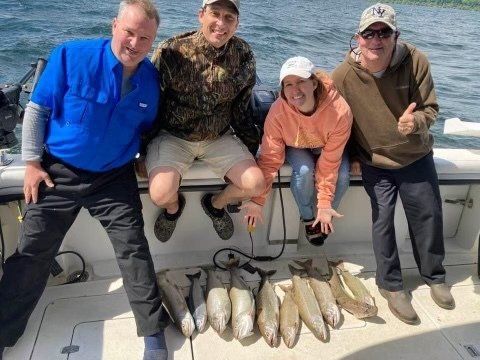 A group of people are posing for a picture on a boat with fish.