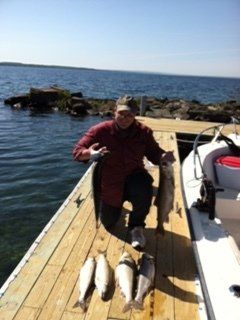 A man sits on a dock holding a bunch of fish
