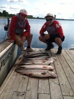 Two men kneeling on a dock with a bunch of fish on it