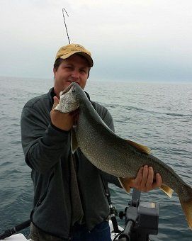 A man is holding a large fish in his hands on a boat
