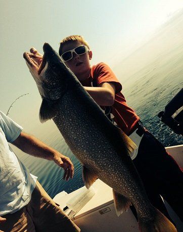 A young boy is holding a large fish on a boat