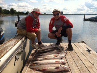 Two men are sitting on a dock with a bunch of fish on it