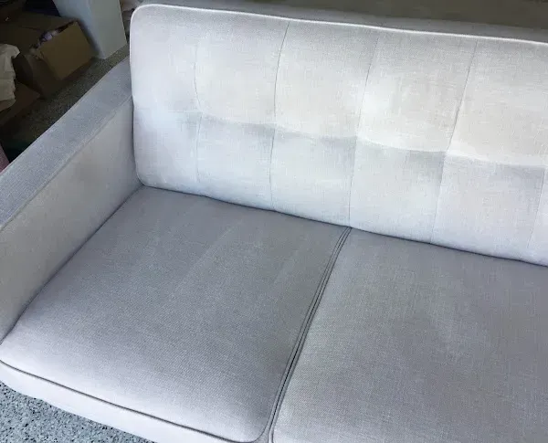 A white couch is sitting on a carpet in a living room.