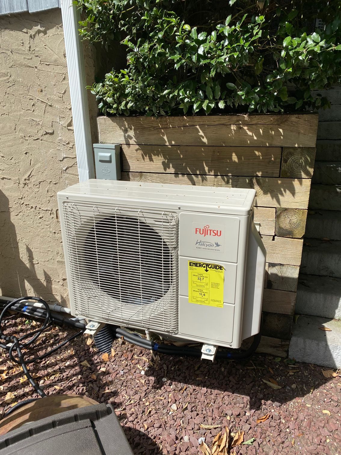 Black wood-burning stove with flames, wood rack, and firewood in a wood-paneled room.