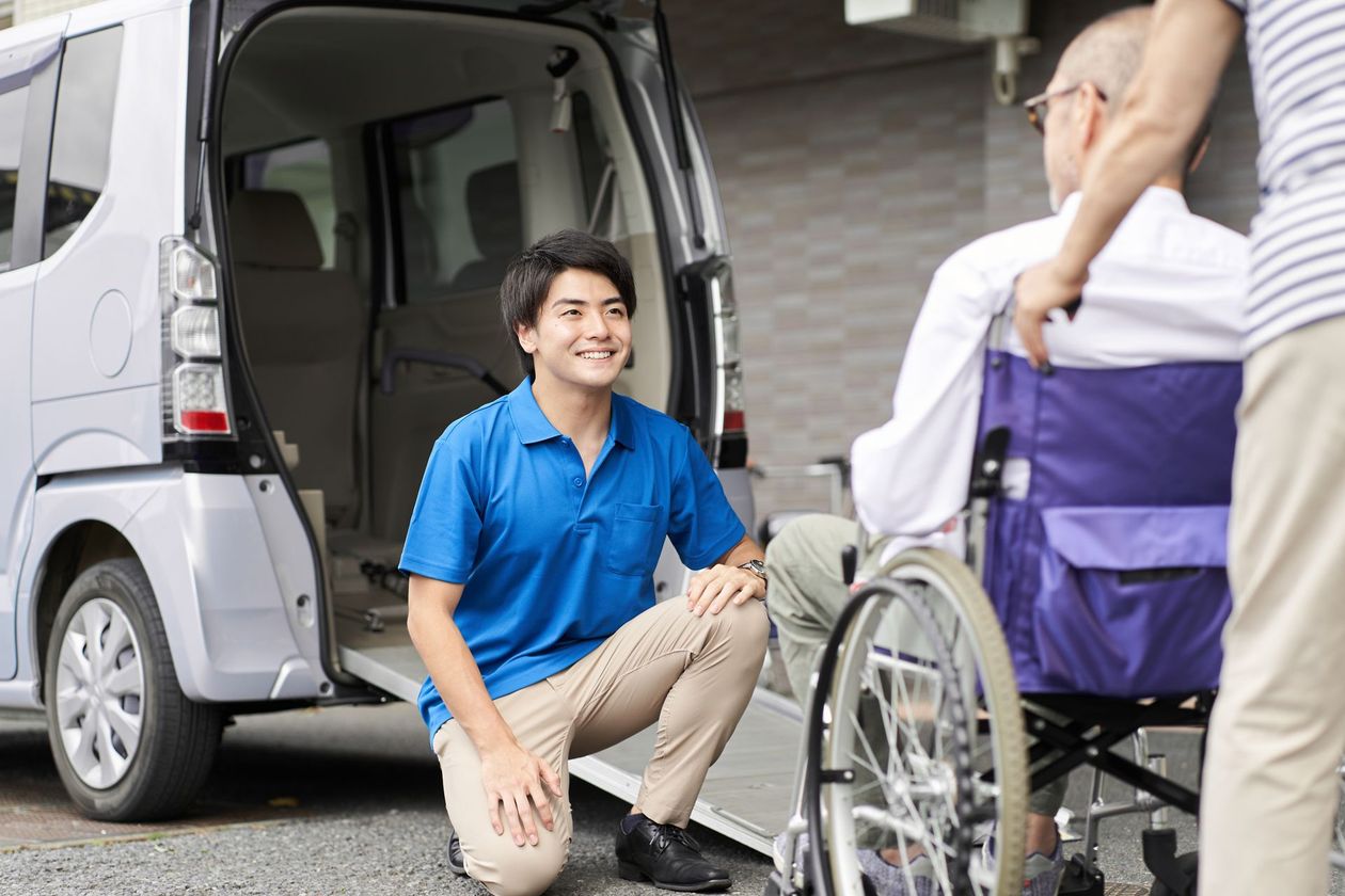 A man is kneeling down next to a man in a wheelchair.