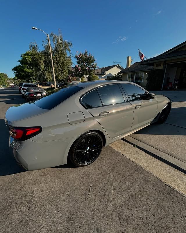 A gray car is parked on the side of the road in front of a house.
