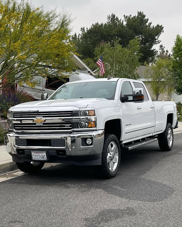 A white truck is parked on the side of the road in front of a house.