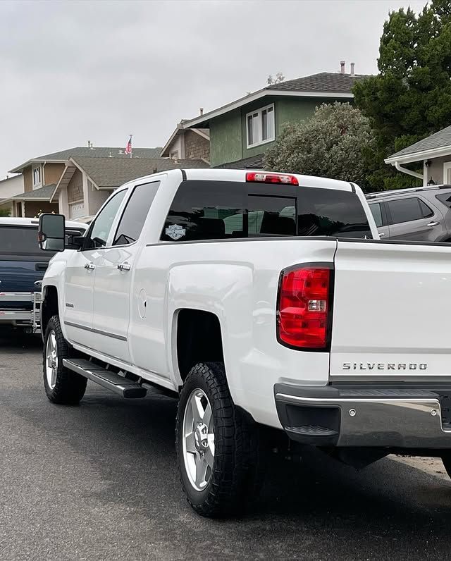 A white truck is parked in a parking lot in front of a house.