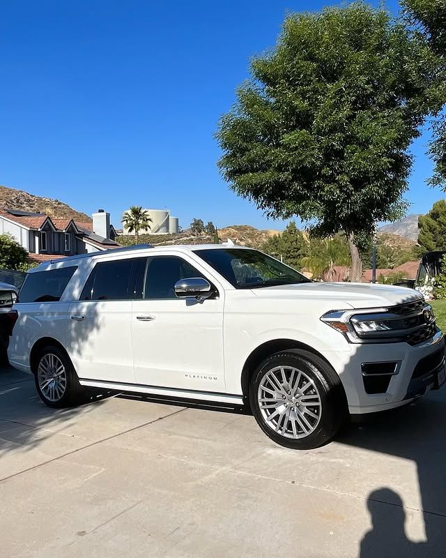 A white suv is parked in a driveway next to a tree.