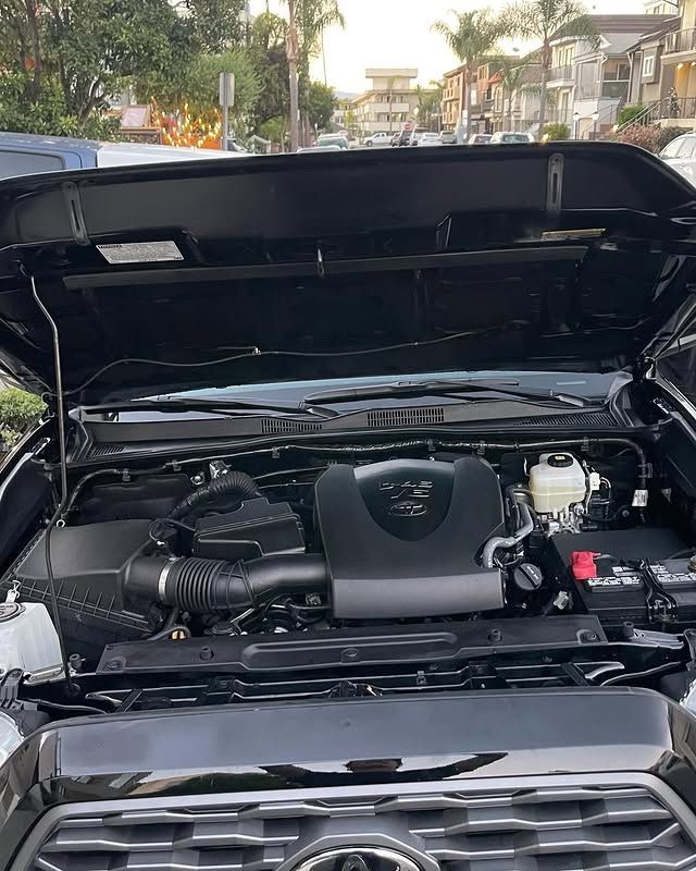 The hood of a black truck is open and shows the engine.