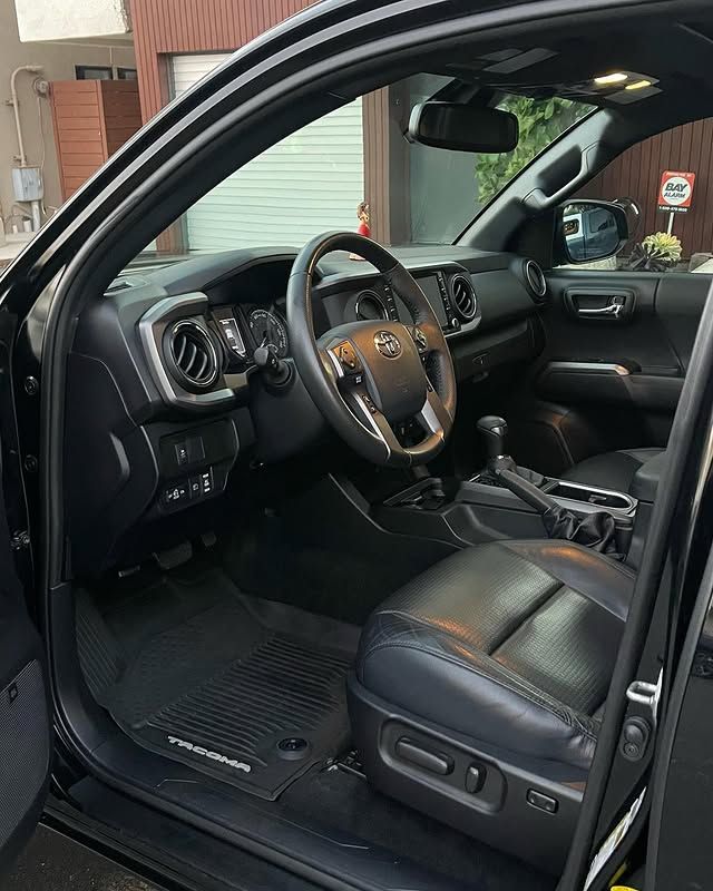 The interior of a black toyota tacoma truck with the door open.