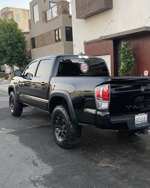 A black truck is parked on the side of the road in front of a building.