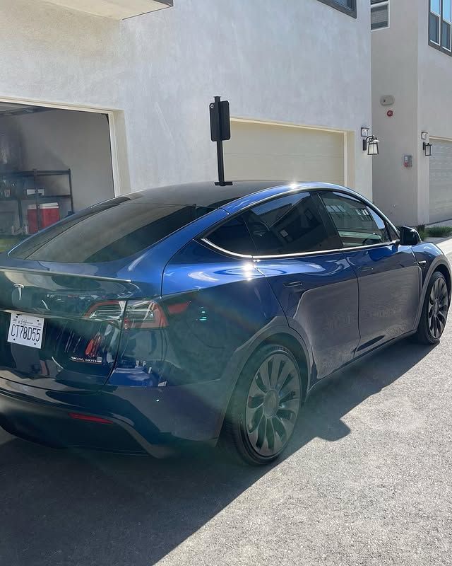 A blue tesla model s is parked in front of a garage.
