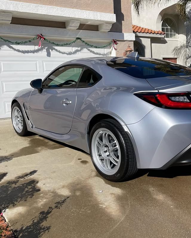 A silver sports car is parked in front of a garage.