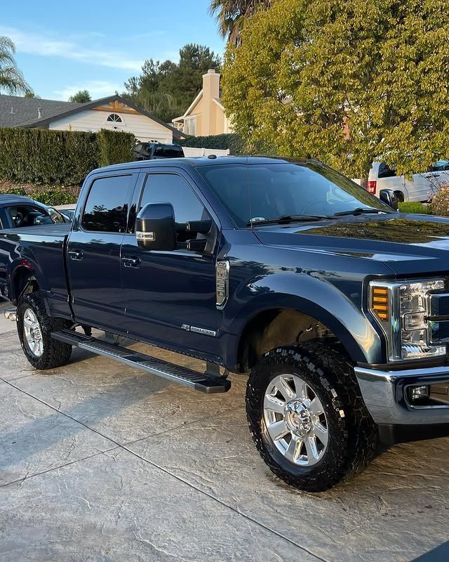 A blue pickup truck is parked in a driveway in front of a house.